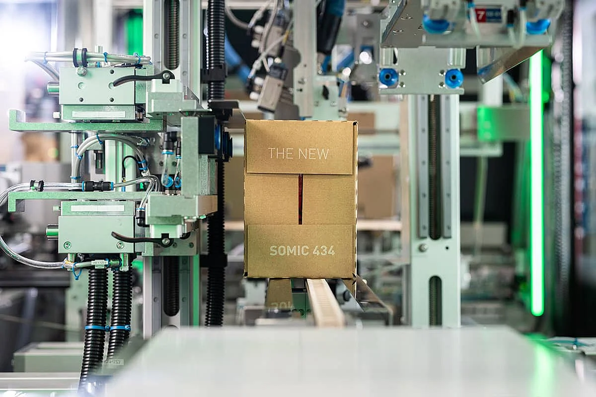 Ein fertig verpackter Wraparound-Karton verlässt die SOMIC 434 Endverpackungsmaschine