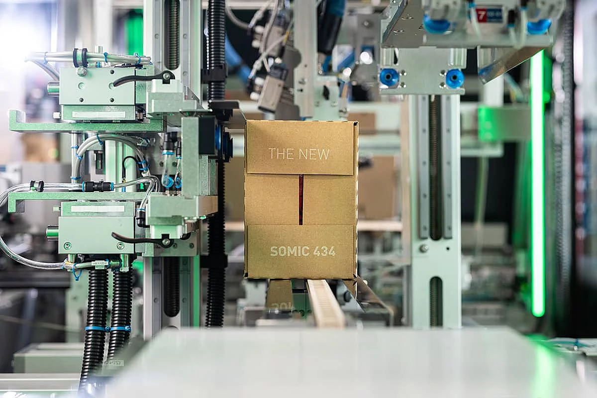 Ein fertig verpackter Wraparound-Karton verlässt die SOMIC 434 Endverpackungsmaschine