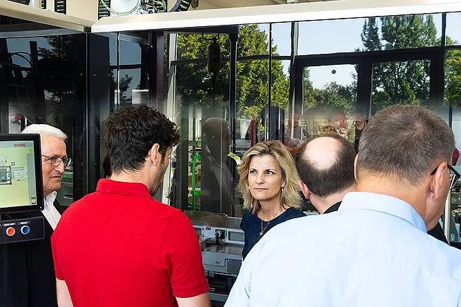 Daniela Ludwig talking with a SOMIC employee in front of a SOMIC packaging machine